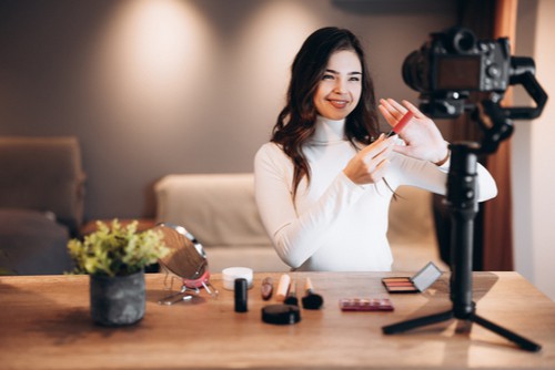 Female taking video of self applying makeup